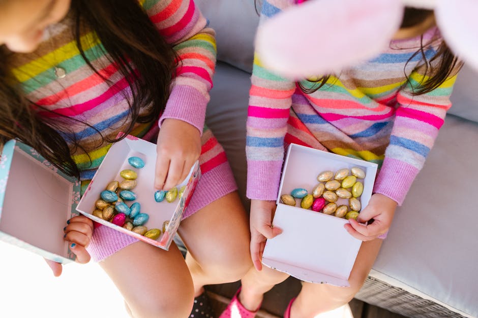 Two children in striped dresses enjoy colorful Easter candies from boxes.