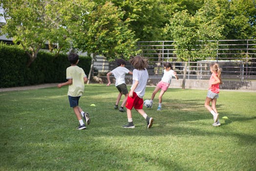 Group of kids having fun playing soccer on a grassy field on a sunny day.