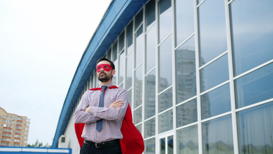 A businessman wearing a superhero costume stands confidently outside a modern office building.