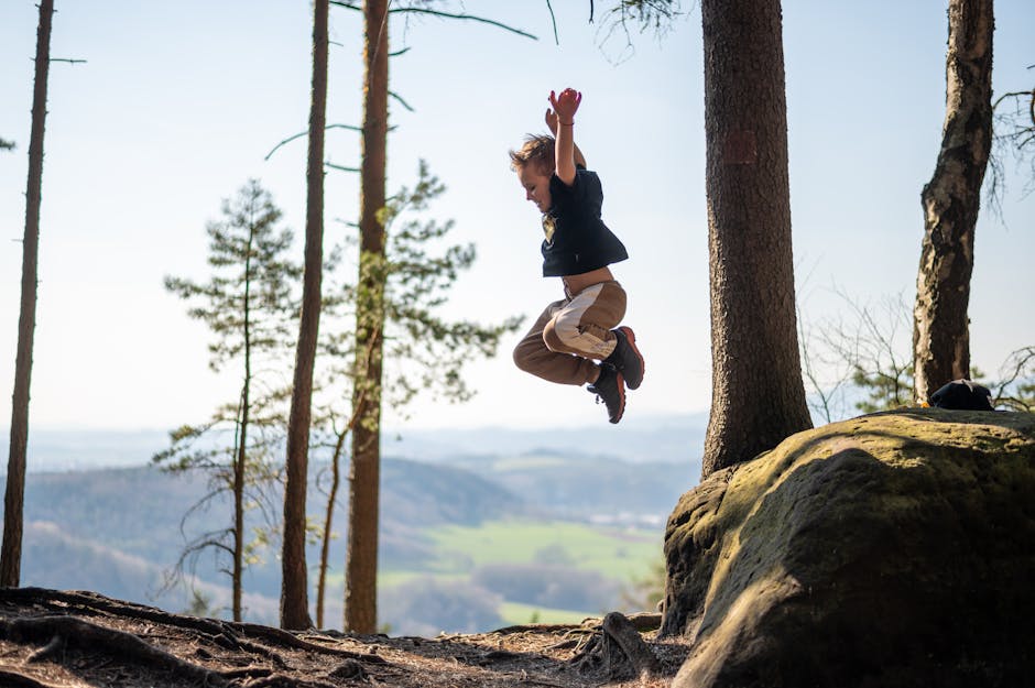 A young boy energetically jumps in a scenic forest. Capturing outdoor fun and adventure.