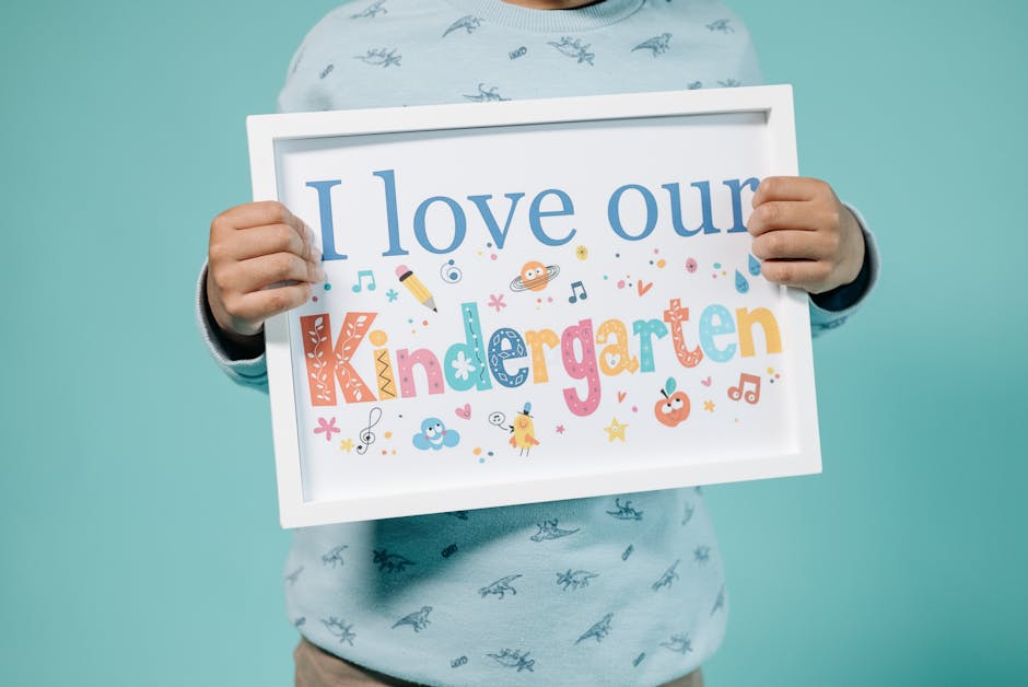 A child holding a colorful educational sign displaying 'I love our Kindergarten' message.
