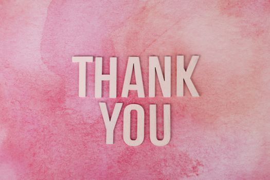 Express gratitude creatively with this 'Thank You' design featuring wooden letters on a pink background.