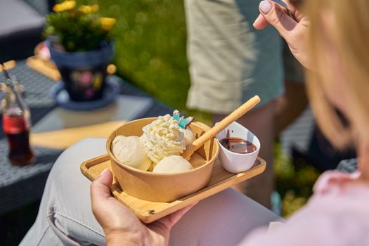Indulge in creamy ice cream with whipped cream and chocolate sauce outdoors.